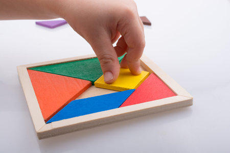 hand holding a missing piece in a tangram puzzle