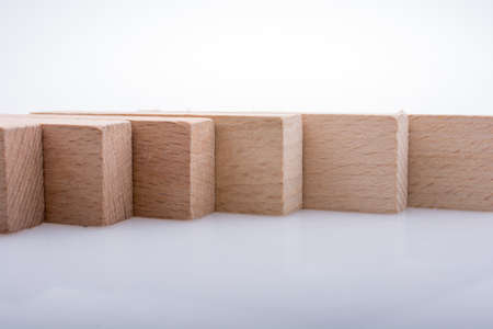 Wooden Domino Blocks in a line on a white backgroundの写真素材