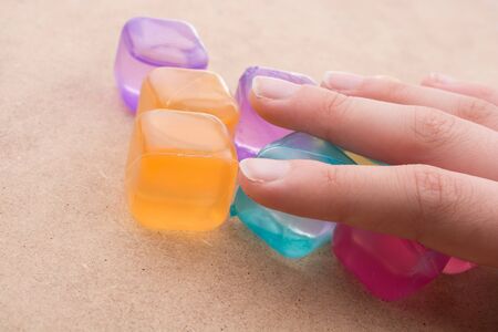 Hand holding  fake colorful ice cubes on brown backgroundの写真素材