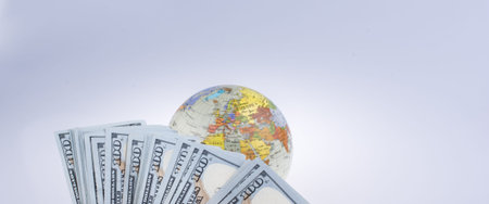 Human hand holding American dollar banknotes by the side of a model globe on white backgroundの写真素材