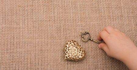 Heart shaped gold color metal object  beside a handの写真素材