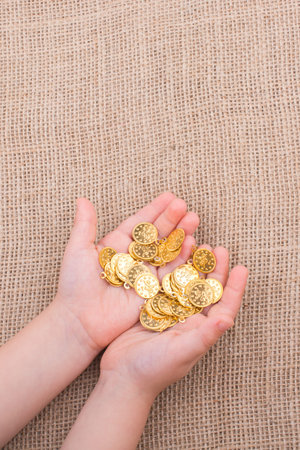 Plenty of fake gold coins in hand on canvasの写真素材