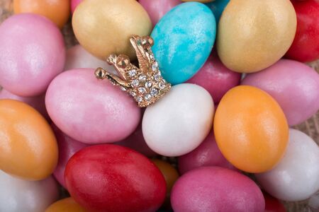 Little model crown placed on colorful candy eggsの写真素材