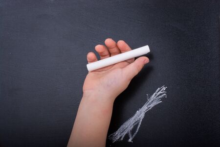 Hand holding  white chalk and black boardの写真素材