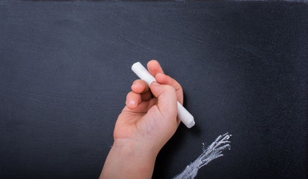 Hand holding  white chalk and black boardの写真素材