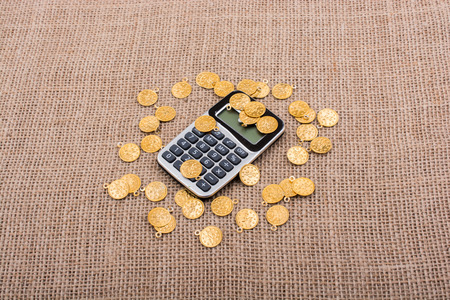 Fake gold coins around the calculator on canvasの写真素材