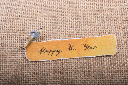Figurine on a Happy new year written torn paper on canvasの写真素材