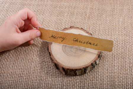 Merry Christmas written on a torn paper on piece of log