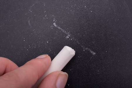 Hand holding  white chalk and black board