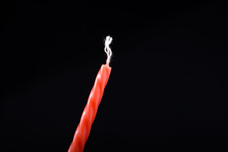 Colorful candle in hand on black background