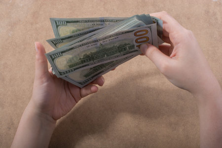 Hand holding American dollar  banknotes isolated on wooden backgroundのeditorial素材
