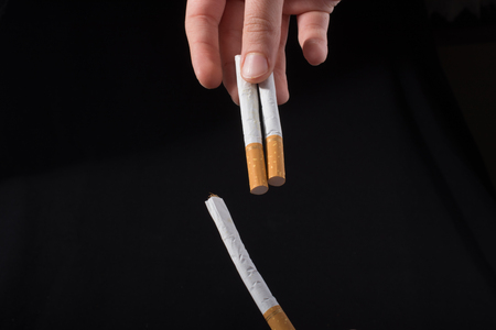 Hand is giving out cigarette on a black backgroundの写真素材