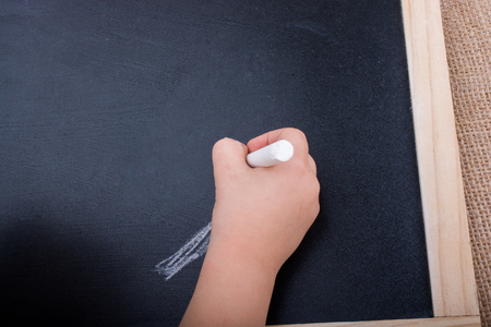 Hand holding  white chalk and black boardの写真素材