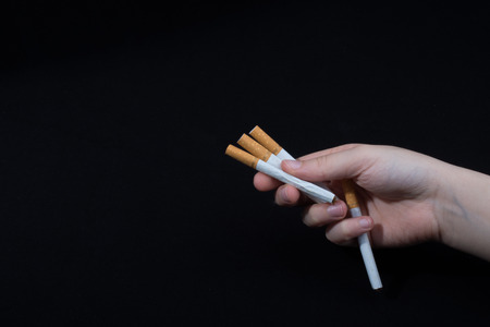 Hand is holding cigarettes on black backgroundの写真素材