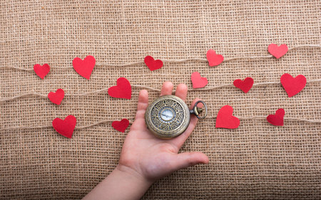 Love concept with pocket watch and  paper hearts on threads