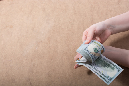 Hand holding American dollar  banknotes isolated on wooden backgroundの写真素材