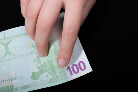 Hand holding 100 euro money  cash isolated on black backgroundの写真素材