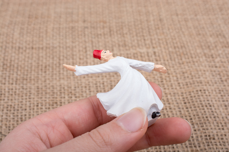 Hand holding a white color Sufi Dervish figurine in handの写真素材