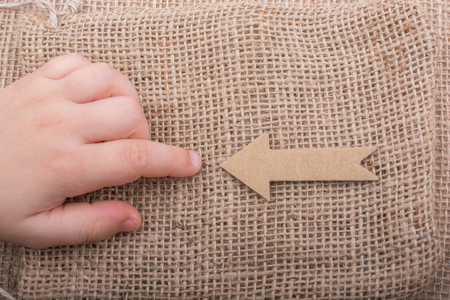 Arrow sign cut out of brown paper on canvasの写真素材