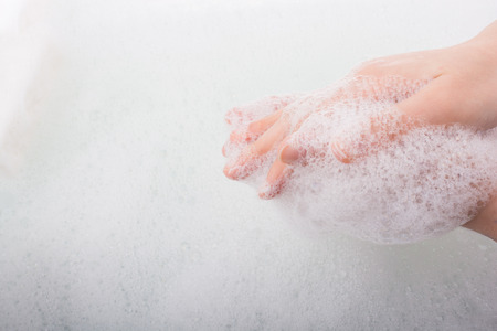 Hand washing and soap foam on a foamy backgroundの写真素材