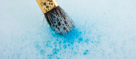 Paint dissolving in water as painting brush touching waterの写真素材