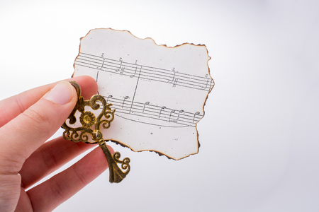 Hand holding a key and burnt paper with musicalの写真素材