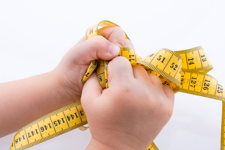 Hand holding a yellow color  measuring tape on a white backgroundの写真素材