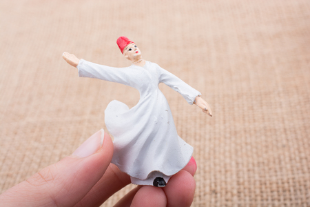 Hand holding a white color Sufi Dervish figurine in handの写真素材