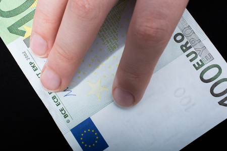 Hand holding 100 euro money  cash isolated on black backgroundの写真素材