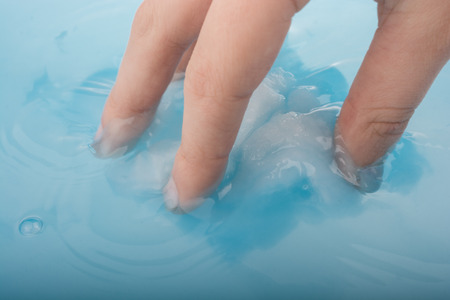 Hand holding some cotton in blue waterの写真素材