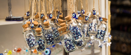 Little transparent glass bottle filled with blue evil eye beadsの写真素材