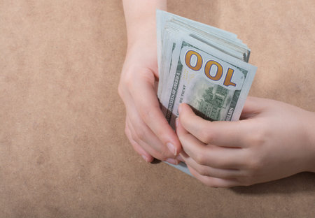 Hand holding American dollar  banknotes isolated on wooden background