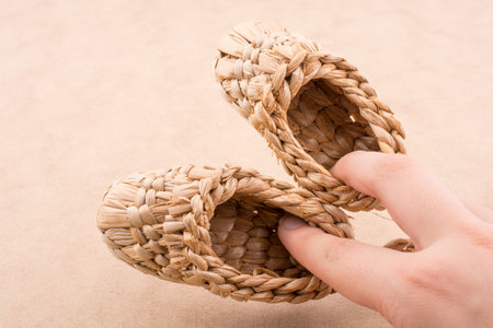 Pair of brown color straw shoes hand on a brown background