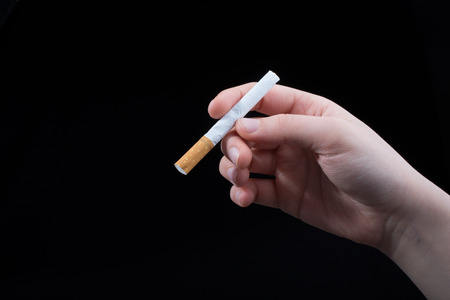 Hand is holding cigarette on a black backgroundの写真素材