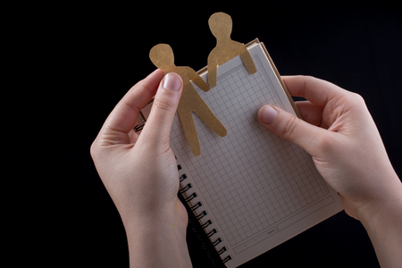 Men shape cut out of paper in notebbok in handの写真素材