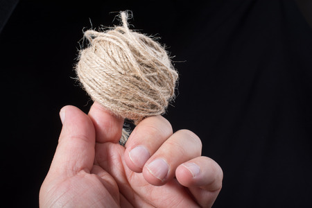 Spool of brown string in hand on black backgroundの写真素材