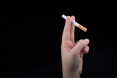 Hand is holding a cigarette on black backgroundの写真素材