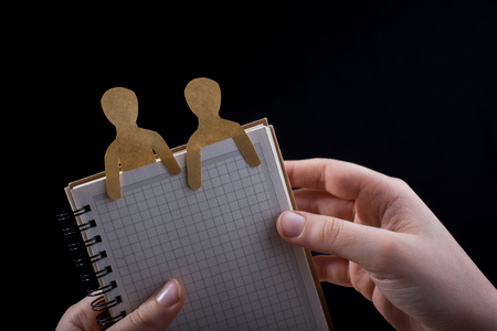 Men shape cut out of paper in notebbok in handの写真素材