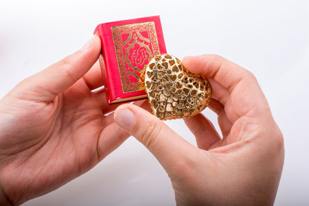 Hand holding Heart shape  and Islamic Holy Book Quran