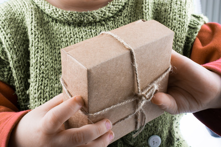 Baby holding a wrapped gift box on white backgroundの写真素材