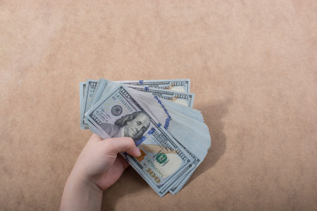 Hand holding American dollar  banknotes isolated on wooden background
