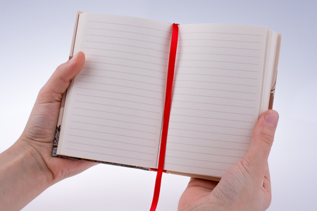 Hand holding a notebook on a white backgroundの写真素材