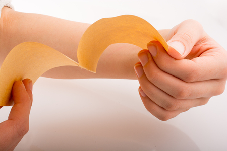 Hand holding a sheet of paper on a white backgroundの写真素材