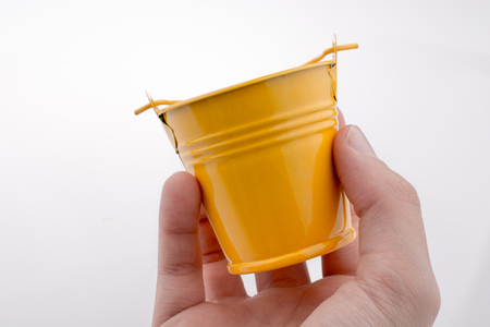 Hand holding a yellow bucket on a white backgroundの写真素材