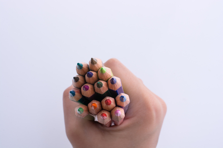 Hand holding color pencils on a white backgroundの写真素材