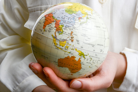 Child holding a small model globe in hand on white backgroundの写真素材