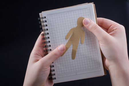 Man shape cut out of paper in notebbok in handの写真素材