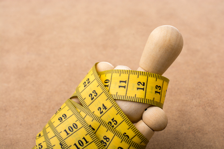 Yellow color measuring tape wrapped on wooden manの写真素材