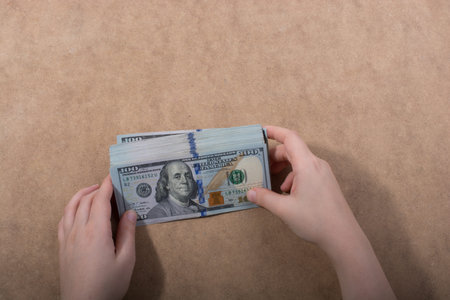 Hand holding American dollar  banknotes isolated on wooden background
