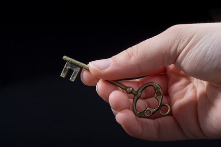 Hand holding a retro styled  golden color   decorative keyの写真素材